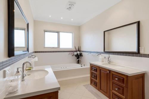 y baño con 2 lavabos, bañera y espejo. en Sorrento Beach Bed & Breakfast, en Perth