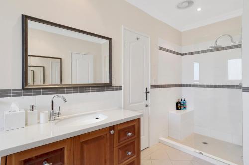 uma casa de banho com um lavatório, um espelho e um chuveiro em Sorrento Beach Bed & Breakfast em Perth
