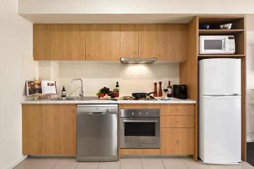 a kitchen with wooden cabinets and a white refrigerator at Quest Mont Albert in Box Hill