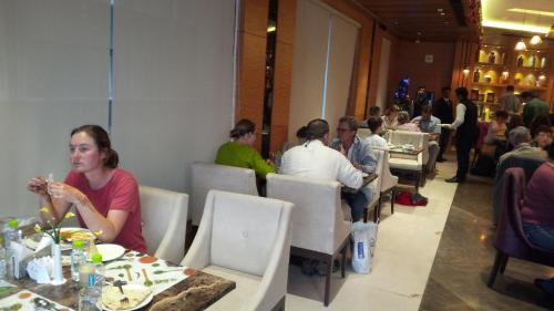 a group of people sitting at tables in a restaurant at Maple Grand in Agra