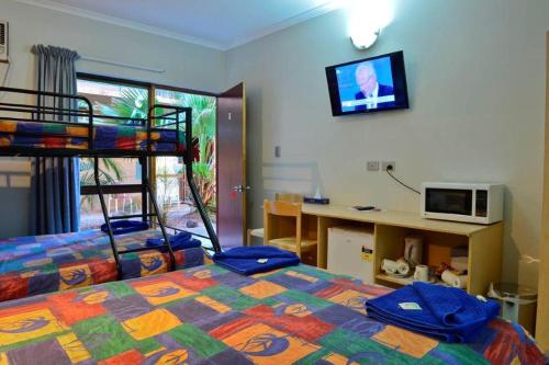 a bedroom with two beds and a desk and a bunk bed at Goldfields Hotel Motel in Tennant Creek