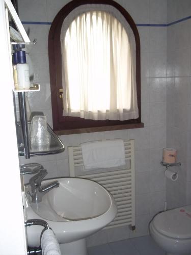 a bathroom with a sink and a toilet and a window at Hotel Cristoforo Colombo in Osimo
