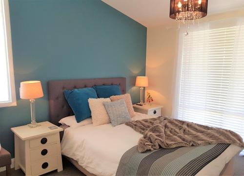 a bedroom with a bed with blue walls and two lamps at Birch Lane in Cradoc