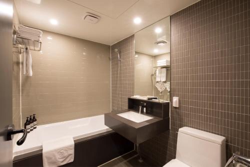 釜山的住宿－貝豪德酒店，带浴缸、盥洗盆和卫生间的浴室