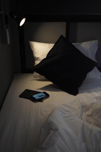 a black pillow sitting on top of a bed at La Malila Hostel in Udon Thani