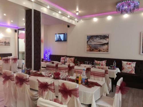 a restaurant with white tables and chairs with pink bows at Aris Hotel Sofia in Sofia