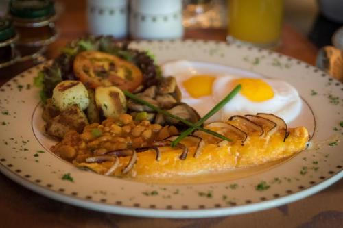 a plate of food with meat and eggs on a table at Summerfield Botanical Garden & Exclusive Resort in Matsapha