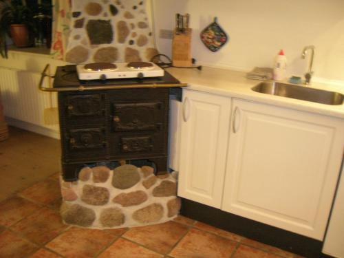 a kitchen with a stone stove and a sink at Vranum Guesthouse in Viborg