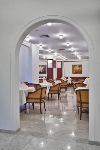 un comedor con mesas y sillas y un arco en Hotel Citrin - Adults Only, en Brasov