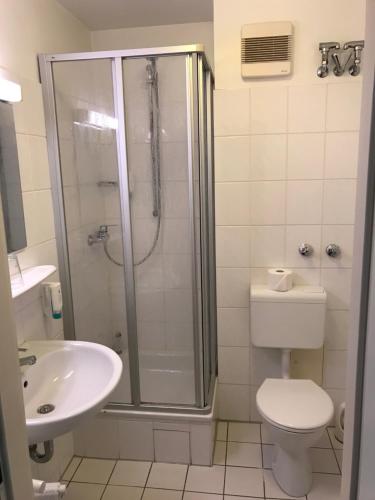a bathroom with a shower and a toilet and a sink at Gästehaus Alpinia in Berlin