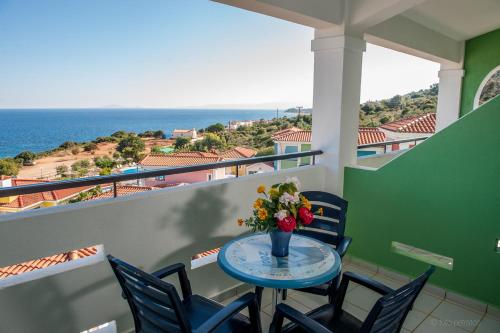 a table with a vase of flowers on a balcony at Porto Skala Village Hotel in Skala Kefalonias