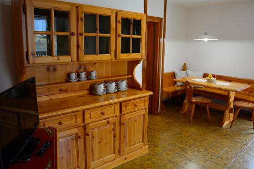 une cuisine avec des placards en bois et une salle à manger avec une table dans l'établissement Pilat, à Vigo di Fassa