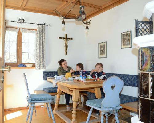施利爾塞的住宿－Ferienhaus Schliersee，坐在桌子上的一名妇女和两名儿童