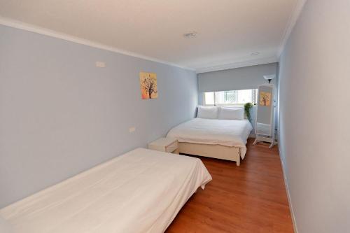 a white bedroom with two beds and a window at May Rooms Taipei NTU in Taipei
