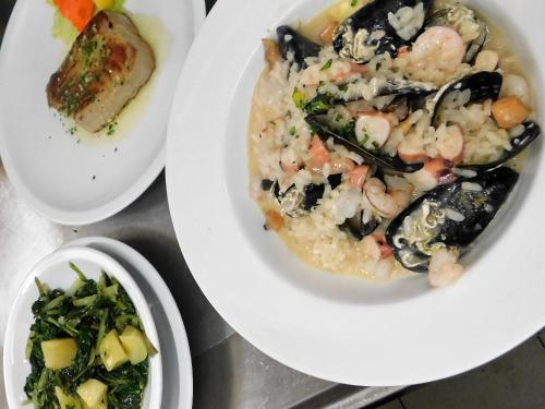 a plate of food with shrimp risotto and a salad at Pension Augustino in Ražanac