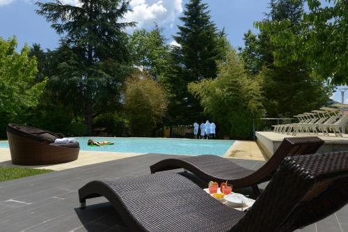 a swimming pool with two chairs and a table with drinks at Atlantic Park Hotel in Fiuggi