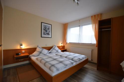 Schlafzimmer mit einem Bett mit weißer Bettwäsche und einem Fenster in der Unterkunft Weingut***Pension Günther Scholtes in Leiwen
