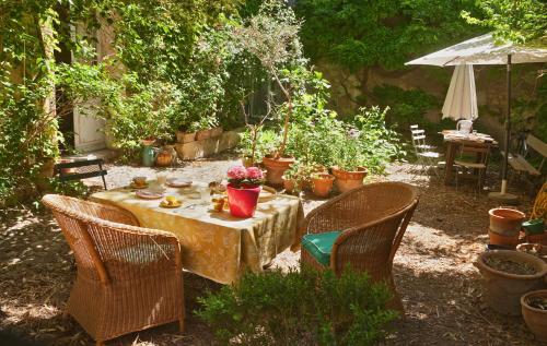 una mesa y sillas en un jardín con plantas en B&B La Vagabonde, en Arles