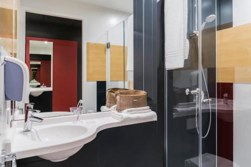 uma casa de banho com um lavatório e uma cabina de duche em vidro. em ibis budget Brugge Jabbeke em Jabbeke