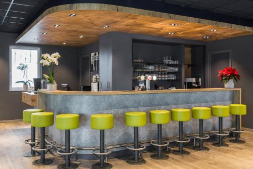 a bar with yellow stools in a room at ibis budget Brugge Jabbeke in Jabbeke