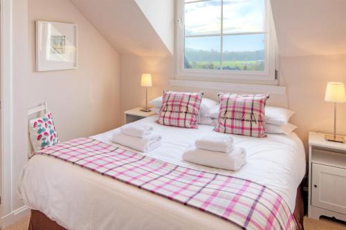 a bedroom with a white bed with pillows and a window at The Square in Kelso