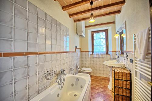 a bathroom with a tub and a toilet and a sink at Casale Santa Francesca by PosarelliVillas in Campiglia dʼOrcia