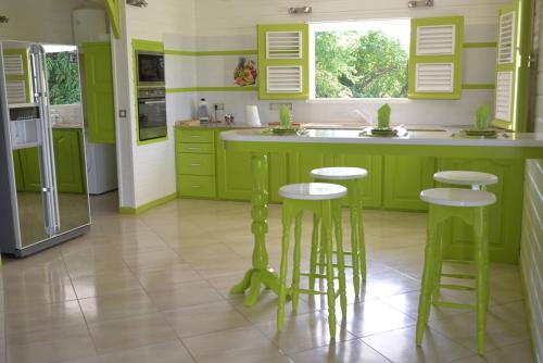 una cocina con armarios verdes y taburetes de bar en Residence Clementine villa Douceur, en Grand-Bourg