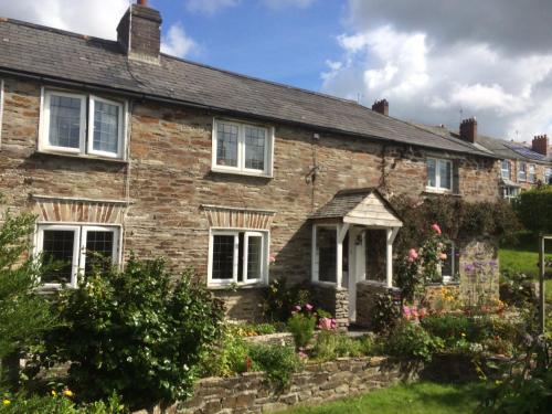 an old brick house with flowers in the front yard at Priory Cottage Bodmin in Bodmin