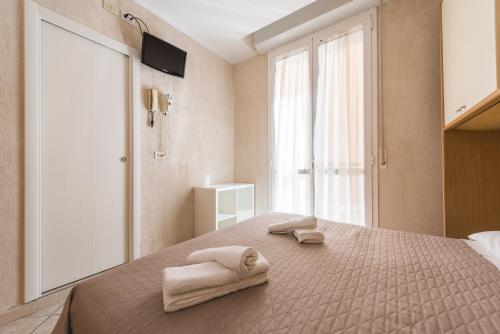 a bedroom with two towels on a bed with a window at Hotel Romina in Rimini