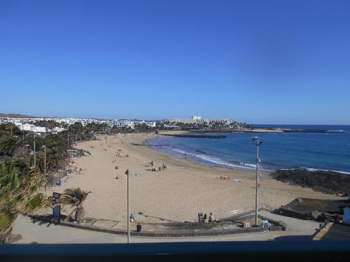 una playa con gente en la arena y el océano en RealRent Costa Teguise Beach, en Costa Teguise