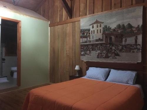 a bedroom with a bed with a painting on the wall at Hostal Kutralwe in Pucón