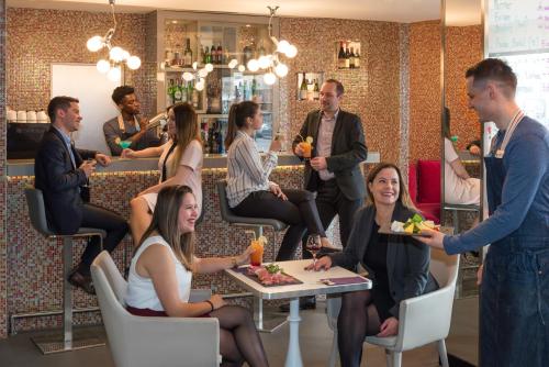 a group of people sitting around a table in a restaurant at Mercure Paris Vaugirard Porte De Versailles in Paris