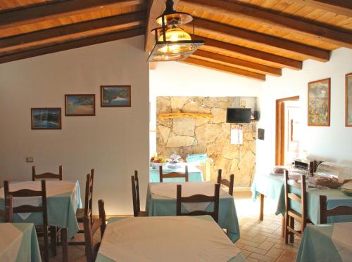 una sala da pranzo con tavoli e un muro in pietra di Hotel Turismo Rurale Villa Maria Caterina a Cala Gonone