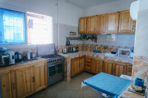 a kitchen with wooden cabinets and a stove at Olas Experience - Tidehunter in Imsouane
