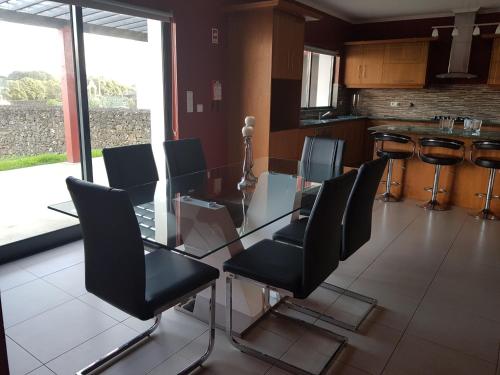 a dining room with a glass table and black chairs at Deluxe Home Praia do Populo in Cabouco