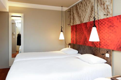 two white beds in a room with two lamps at ibis Besançon Centre Ville in Besançon