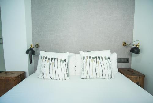 a white bed with white pillows on it at The Lights City Rooms in Málaga