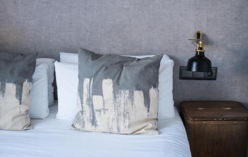 a bed with white sheets and pillows with a lamp at The Lights City Rooms in Málaga