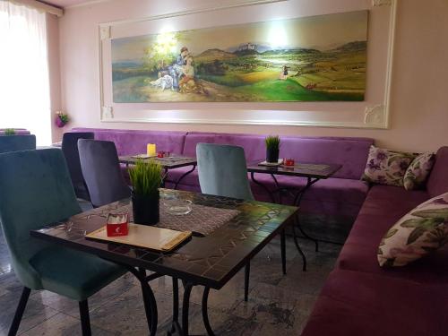 a dining room with a purple couch and a table and chairs at Bed & Breakfast Vila Stanišić in Požega