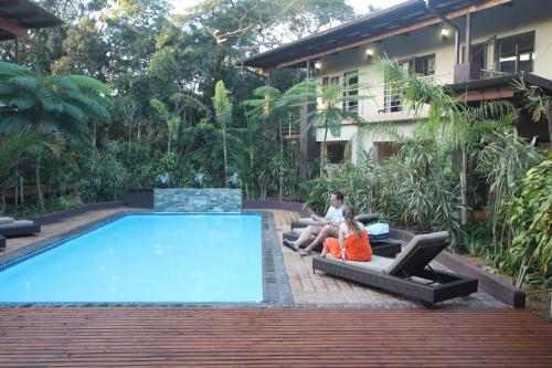 two women sitting on lounge chairs next to a swimming pool at Forest Lodge in St Lucia