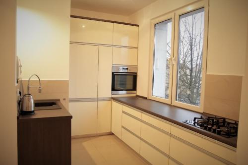 una cocina con armarios blancos y una ventana en Apartament Aesthetic, en Tychy