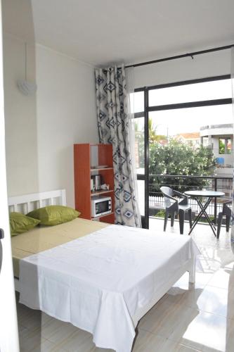 a bedroom with a white bed and a balcony at Ashmara Villa & Studio in Flic-en-Flac