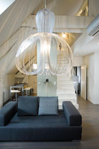 a living room with a blue couch and a chandelier at Maison d'Hôte de Myon in Nancy