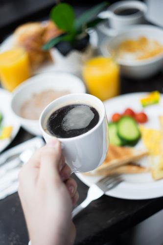 una persona che tiene una tazza di caffè sul tavolo di Kensington Prime Hotel a Londra