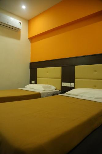 two beds in a room with orange walls at Hotel Sabareesh Plaza in Madurai