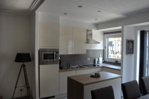 une cuisine avec des placards blancs, une table et une fenêtre dans l'établissement Oostende Appartement, à Ostende