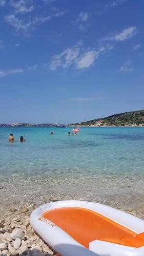 a surfboard on the beach with people in the water at Apartments Anka in Vinišće