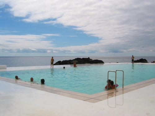 a group of people in a swimming pool near the ocean at Casa da Ribeira in Lajes do Pico