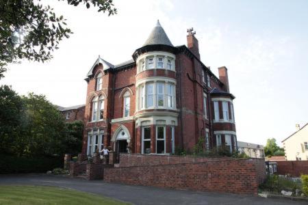 a large red brick building with a tower on top at Salfordian in Southport