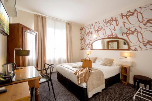トゥールーズにあるオテル レイモンド 4 トゥールーズのベッドとデスクが備わるホテルルームです。